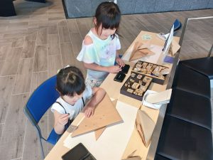 紙かぶとにスタンプを押す作業をする女児二人