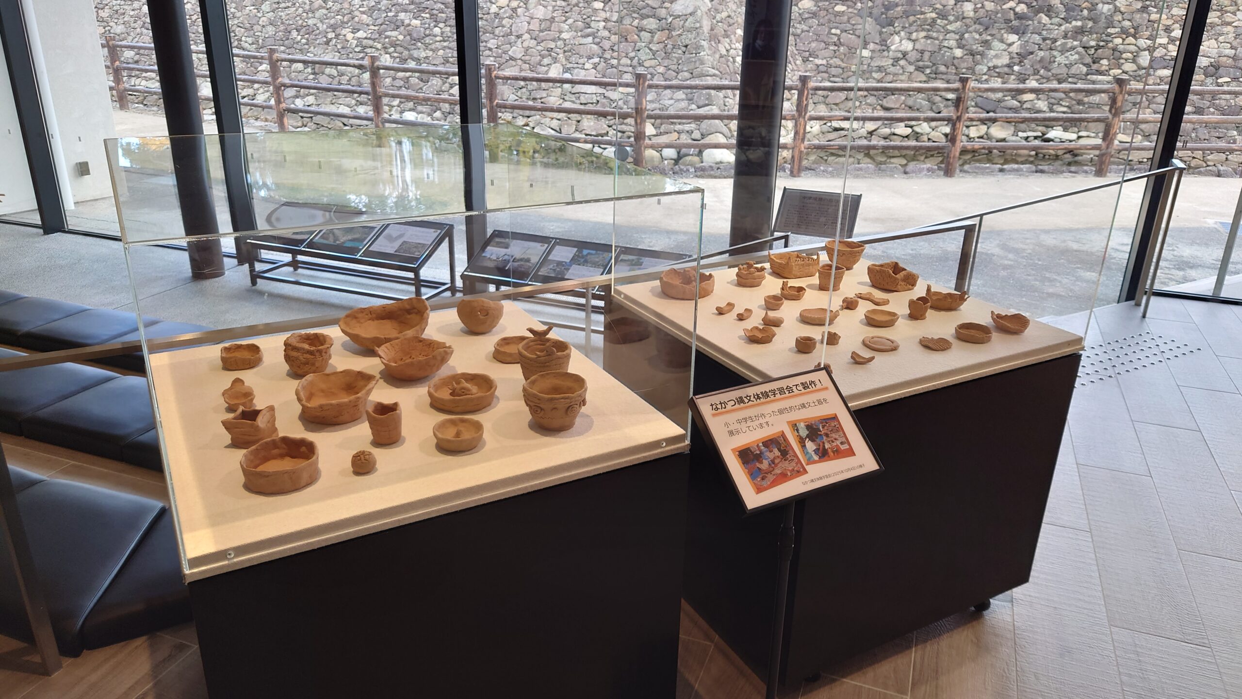 土器が展示ケースの上に並べられている様子。ケースは2つ